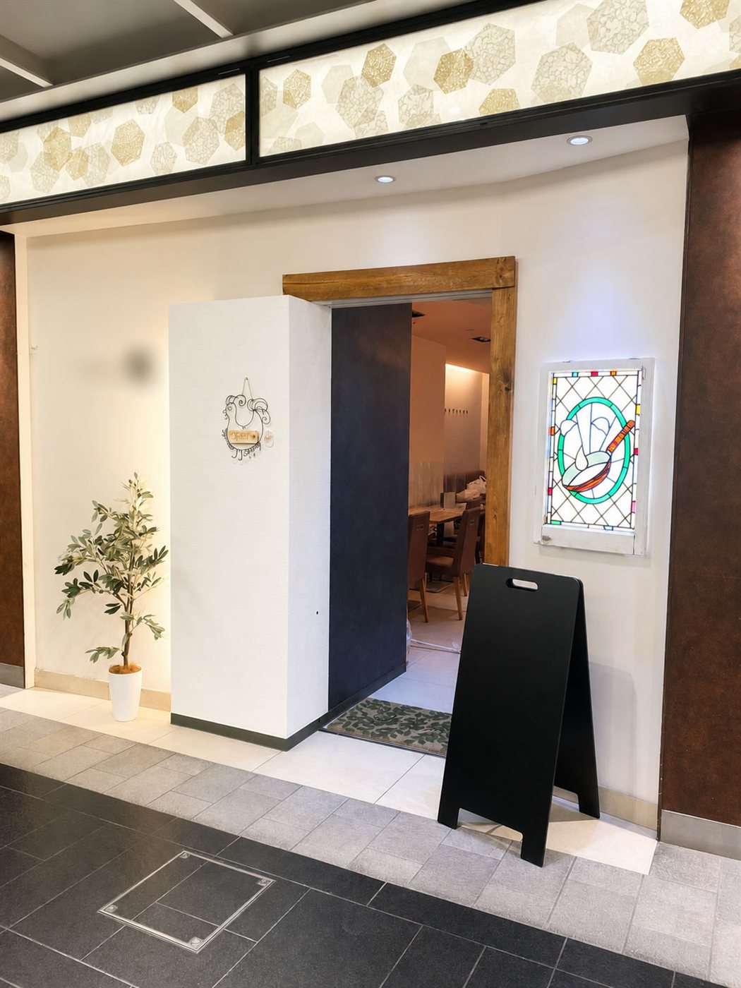 改装後の洋食店エントランスを斜めから見た様子。無垢材の枠の出入口と、その右手に背面から照らしたステンドグラスが並んでいる